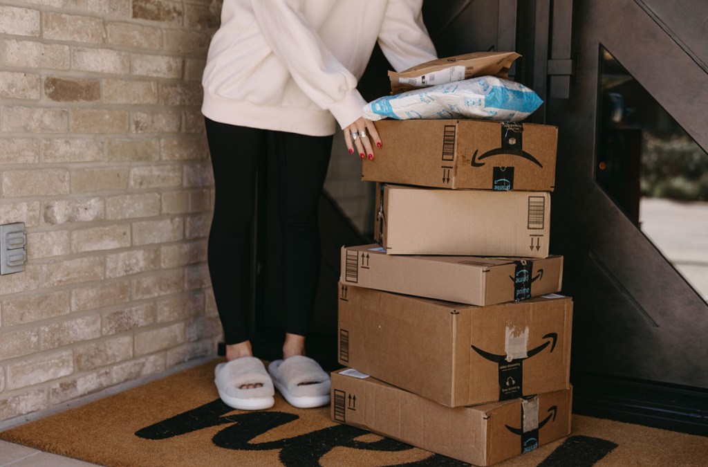woman next to stack of amazon boxes