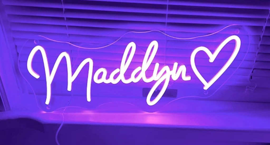 purple neon maddyn name sign with heart on window sill