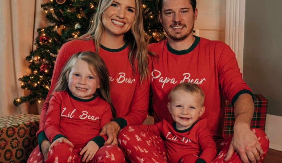 a family of four in matching pajamas in front of a christmas tree