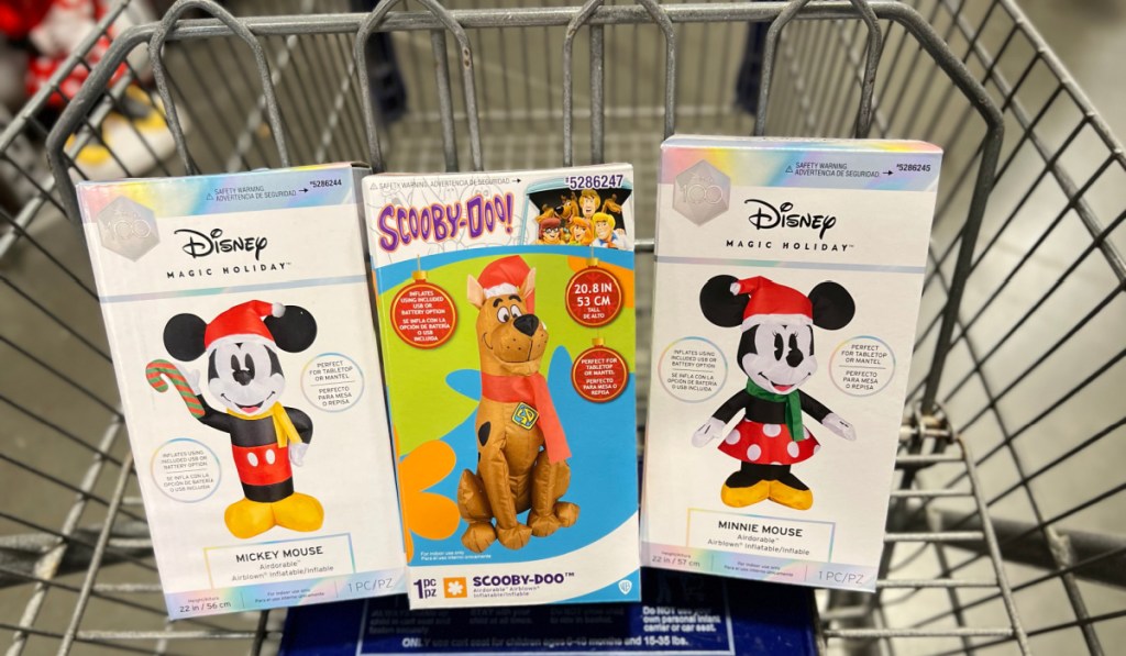 boxes of inflatable disney and scooby doo inflatables in a lowes shopping cart