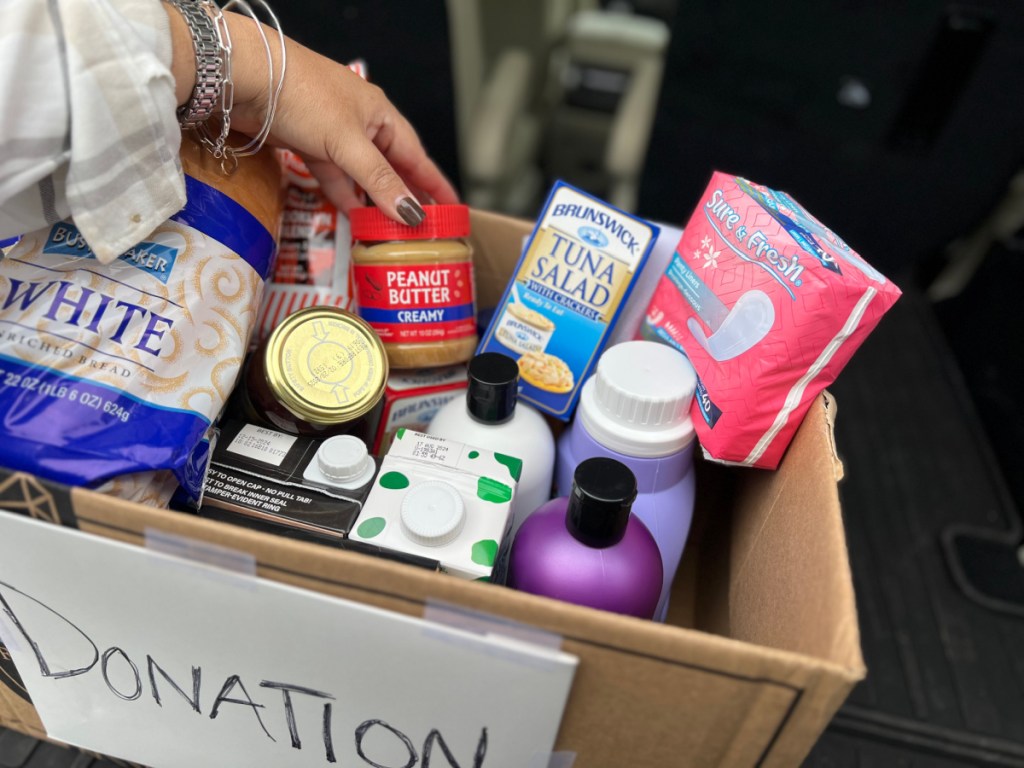 woman adding items to a full box of donations