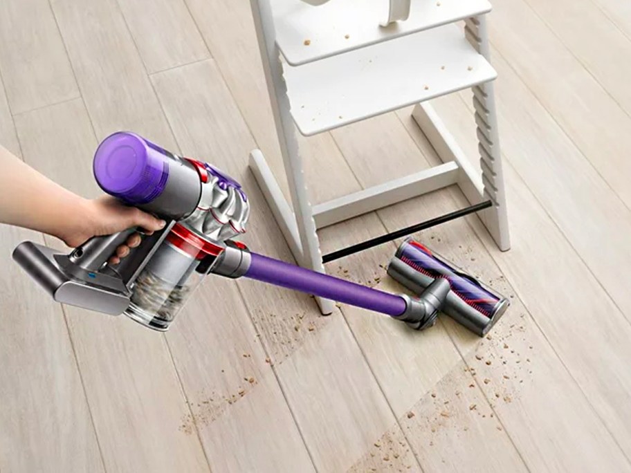 woman using dyson vacuum on floor in front of white highchair