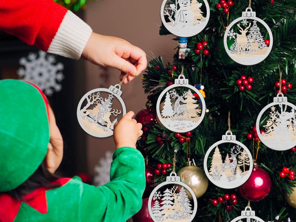 child putting ornament on tree