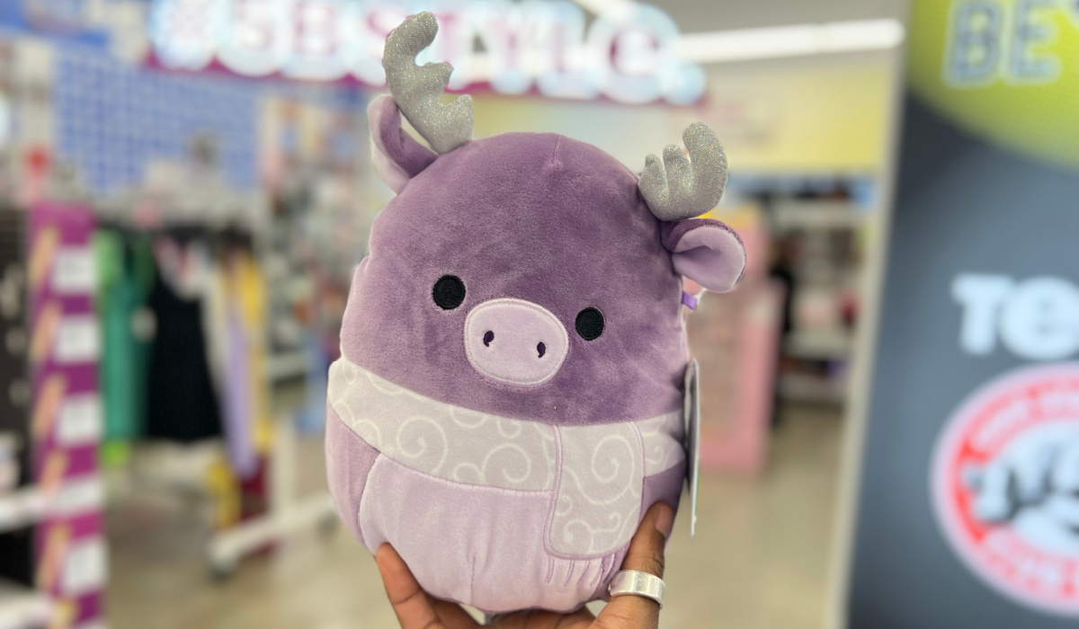 hand holding up a purple squishmallows winter moose in a five below store