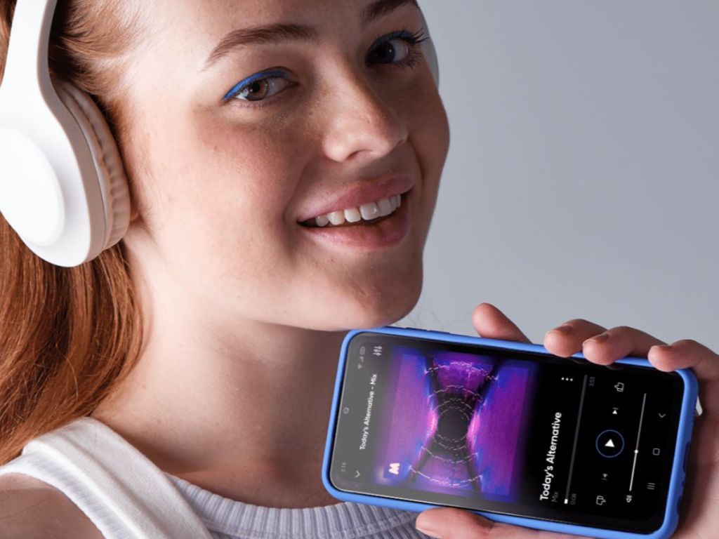 girl with white headphones on holding phone