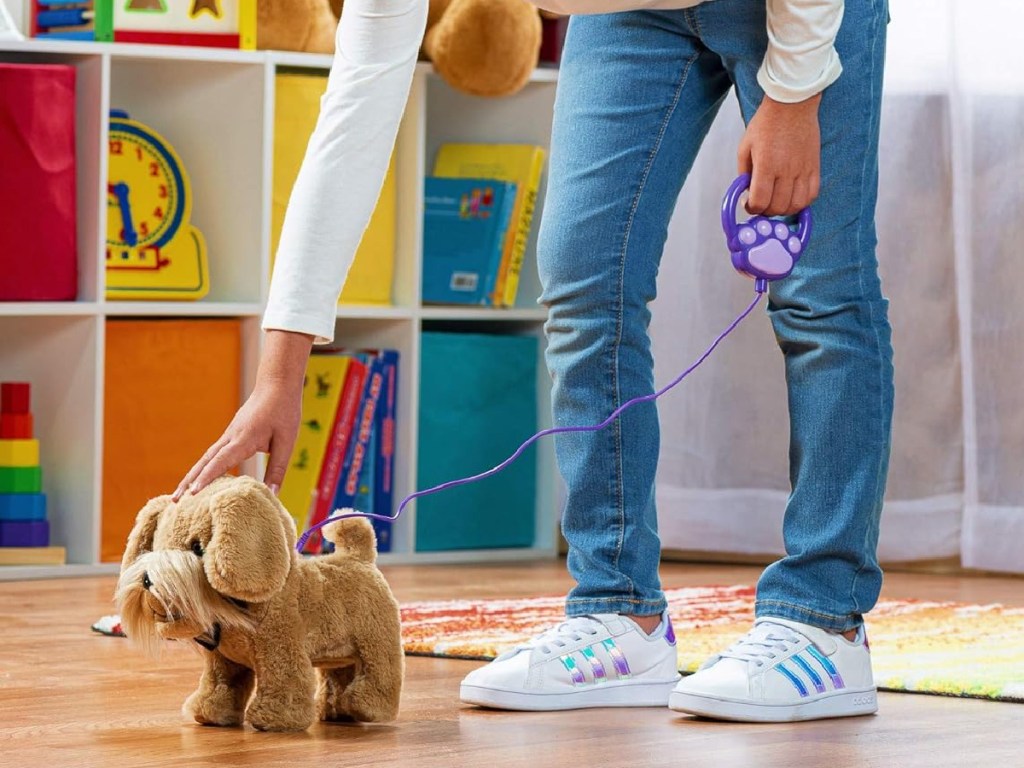 girl petting toy dog with a leash around its back