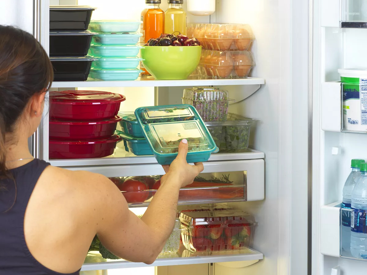 woman putting meal prep container in fridge