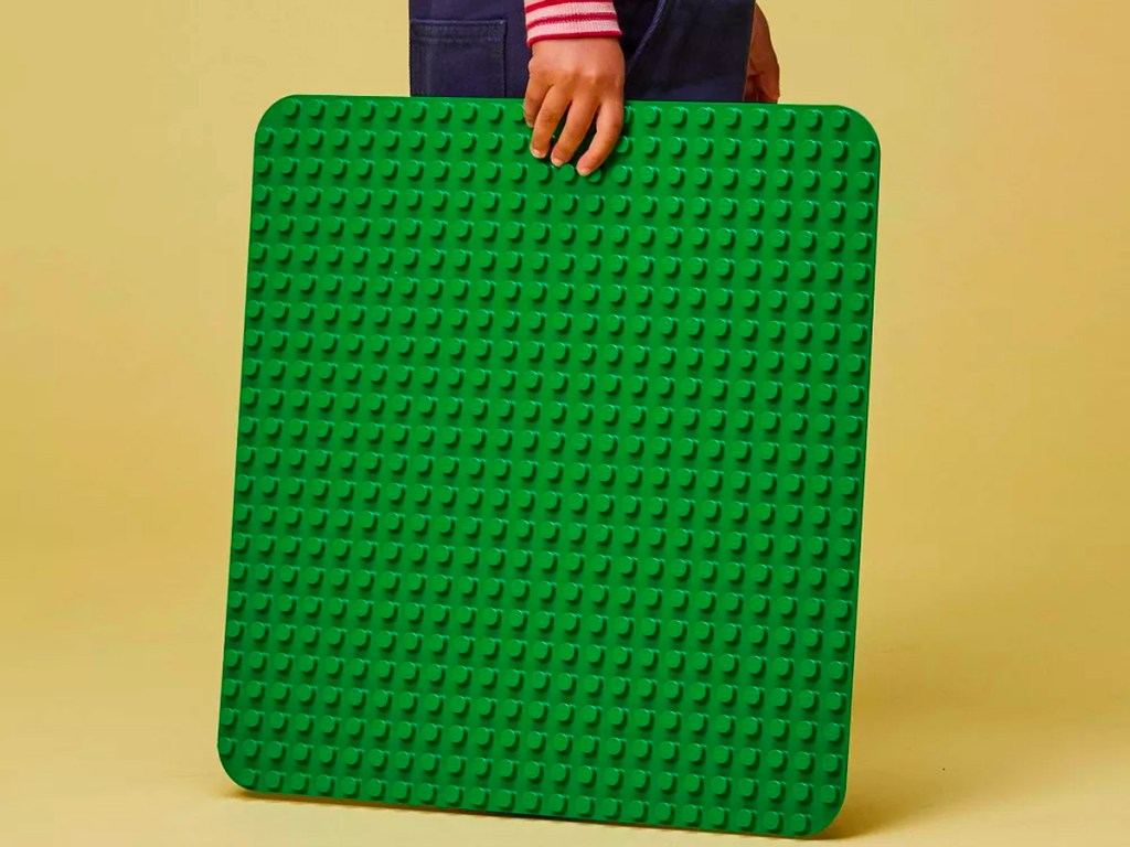kid holding green lego duplo baseplate