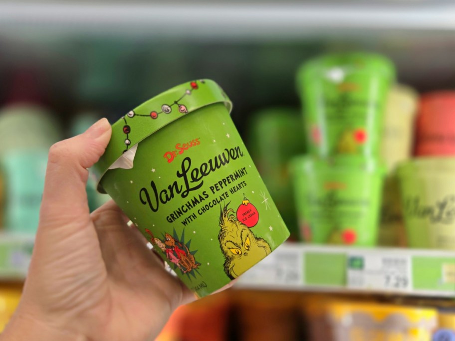 A hand holding up a pint of Grinchmas ice cream.