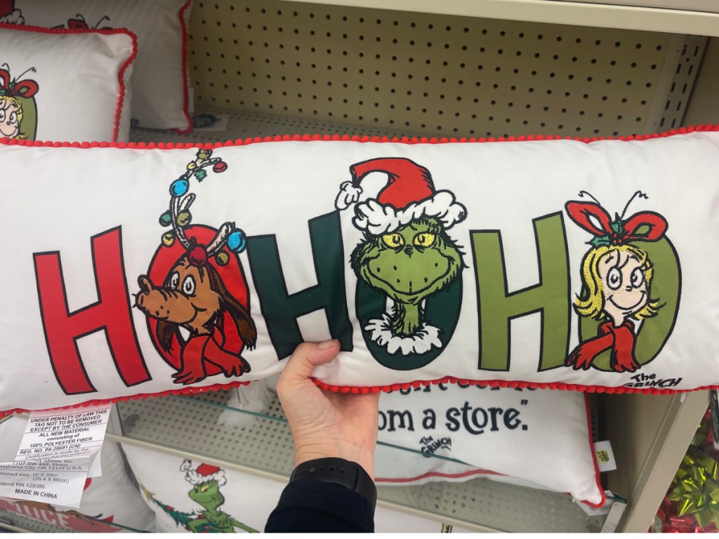 hand holding the grinch ho ho ho pillow at the store