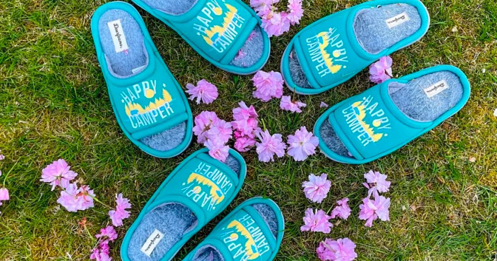 happy camper slippers sitting on grass with purple flowers