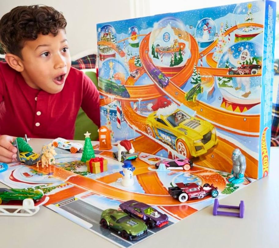 a little boy playing with a hot wheels advent calendar