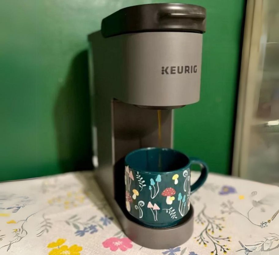 a gray keurig k mini go coffee maker with a mug on the drip tray