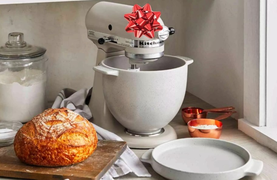 beige kitchenaid stand mixer with bread bowl on kitchen counter with red bow and fresh baked breads