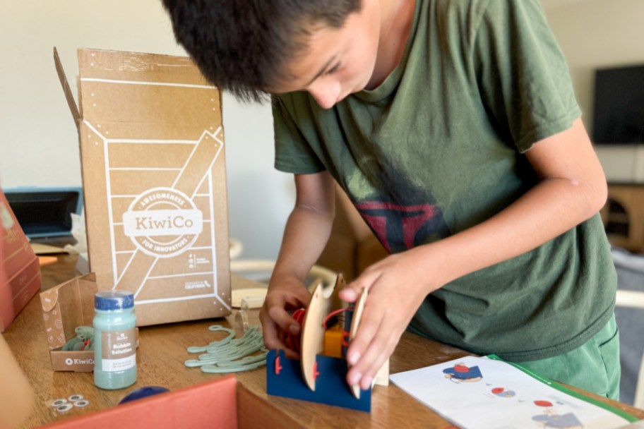 boy building small machine next to box