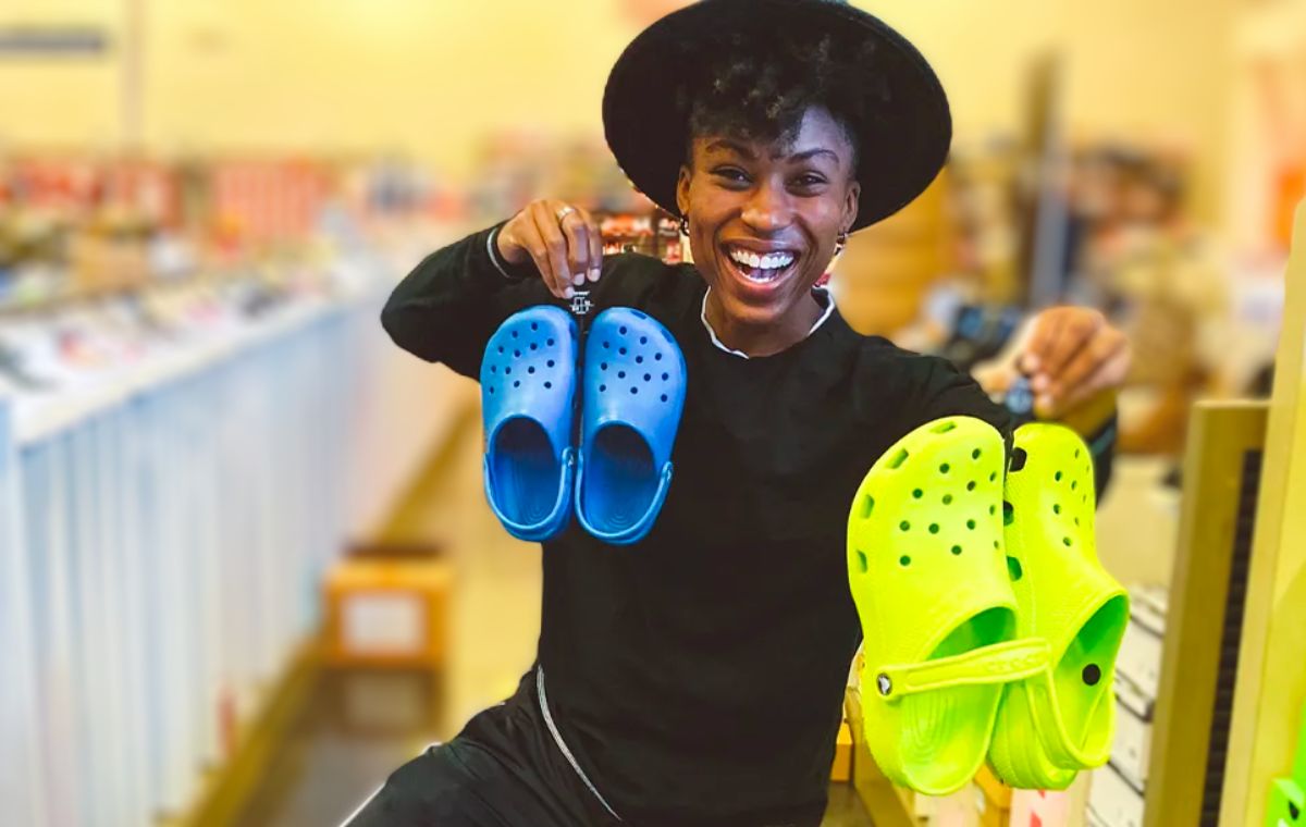 lady in a store holding 2 pair of crocs