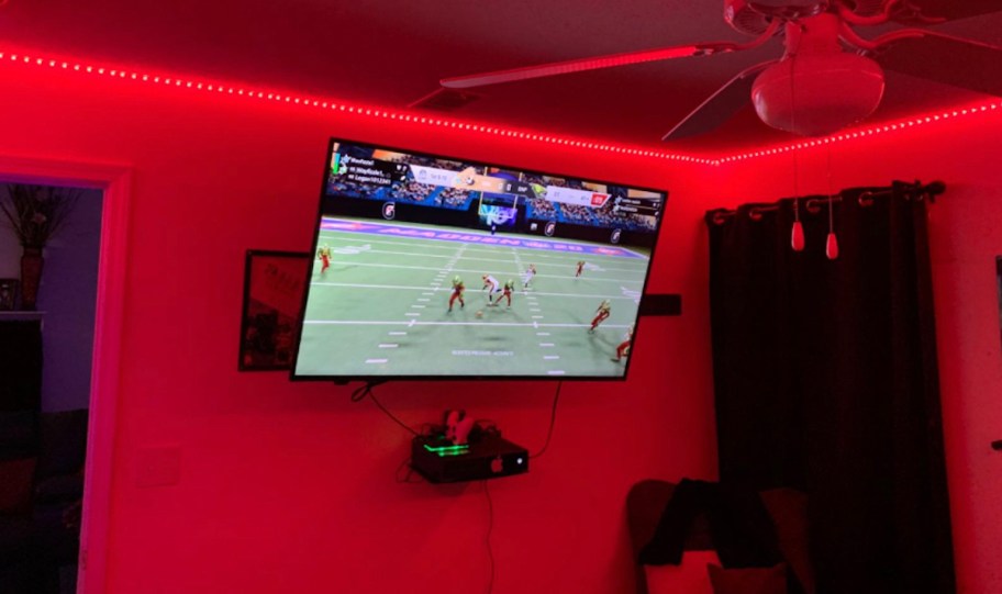 red led strip lights along ceiling in room with tv on wall