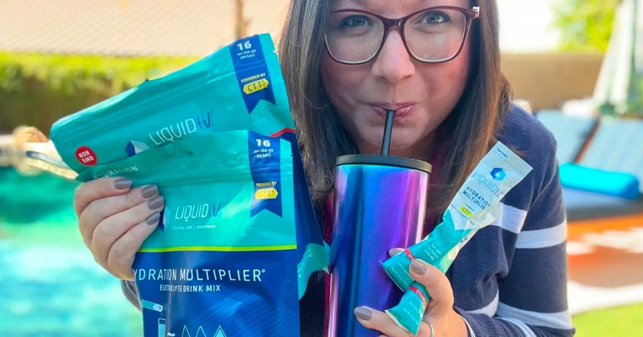 woman holding two liquid iv 16 packs and tumbler