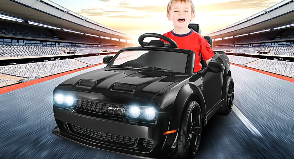 little boy inside of ride on car with racetrack in the background