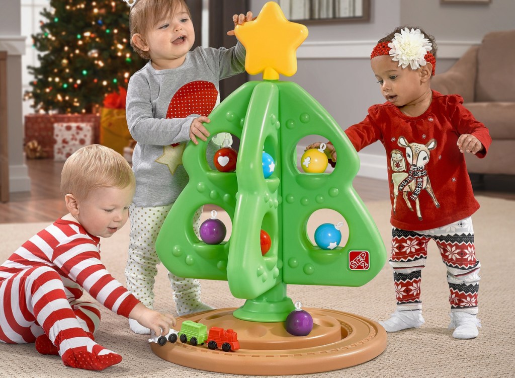 little girl playing with Christmas tree and the train underneath it