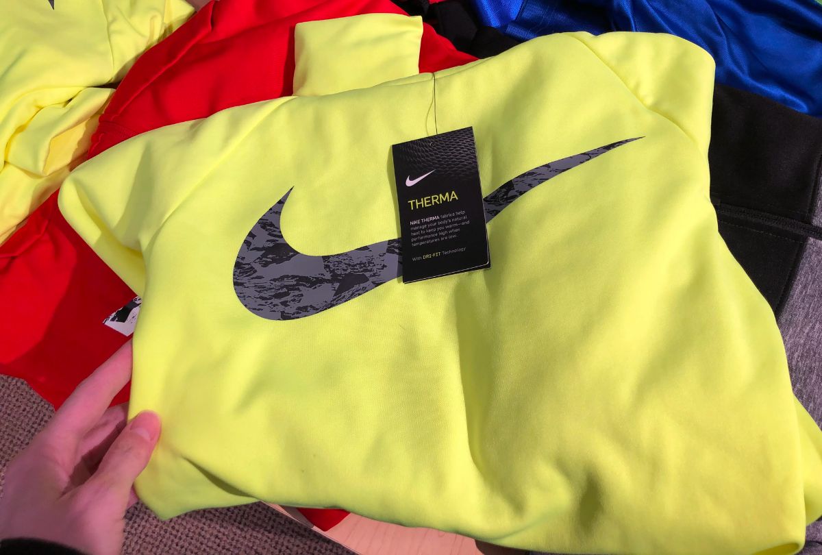 a woman's hand holding a yellow nike hoodie