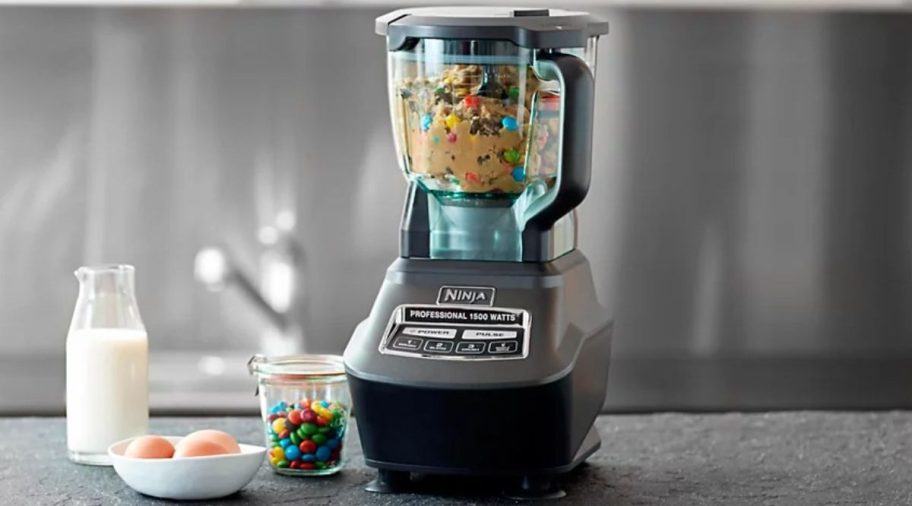 A ninja pro mega kitchen system blender on a kitchen counter next to baking ingredients for cookies