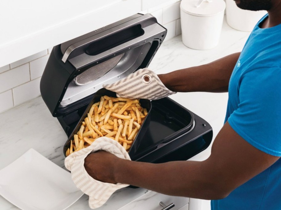 person taking tray of fries out of air fryer
