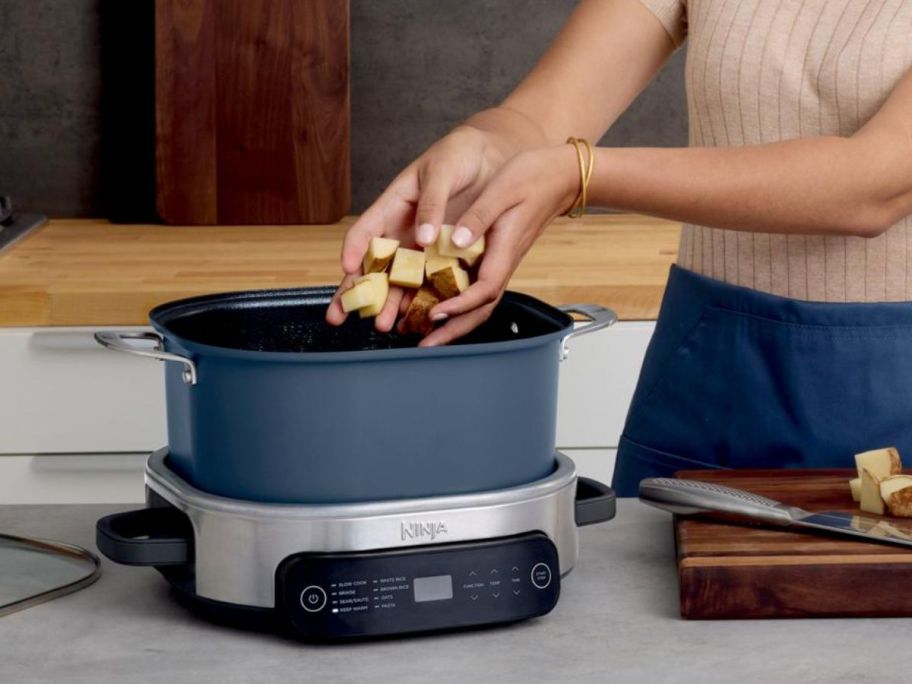 a woman adding potatoes to a blue cooking pot