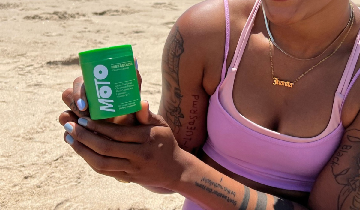 woman holding green vitamin bottle on beach