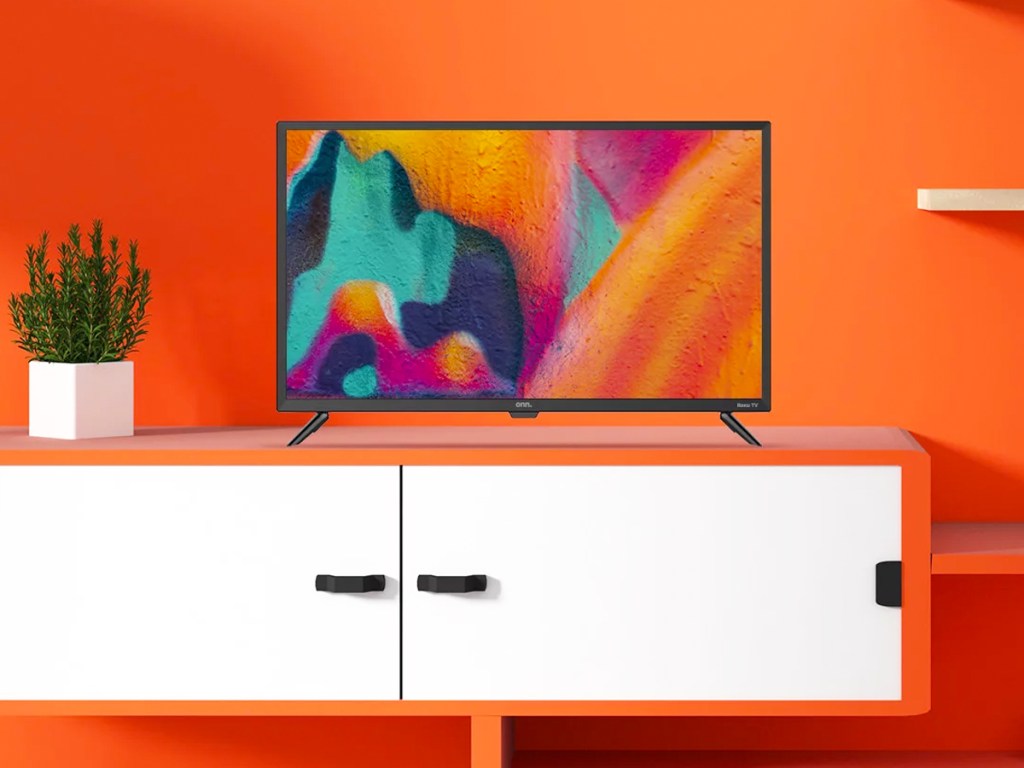 tv on a white tv stand in room with orange wall