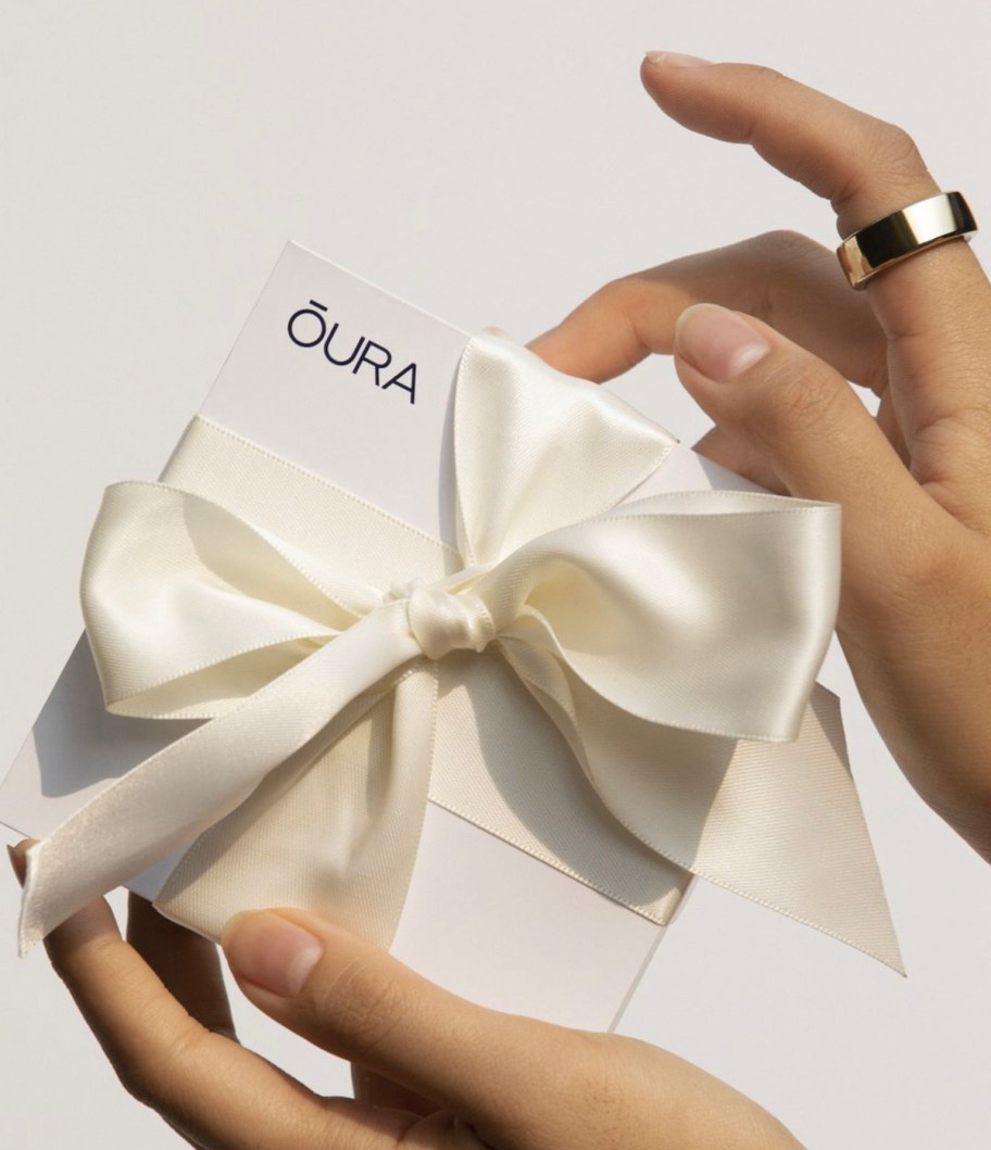 hands holding oura gift box wearing silver ring on pointer finger