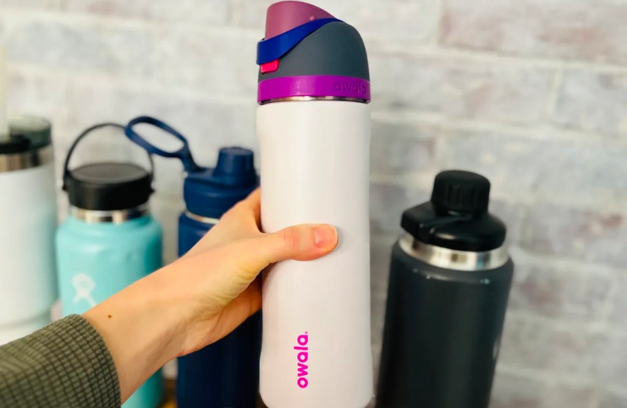 hand holding white and purple owala water bottle