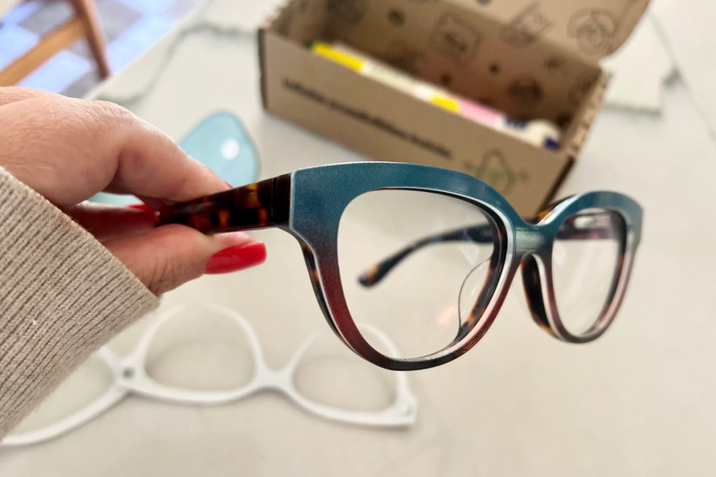 hand holding pair of teal glasses