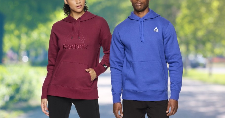 woman wearing a wine reddish purple color Reebok hoodie and man wearing a bright blue Reebok hoodie