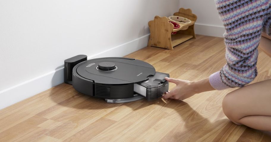 women taking out tray on a roborock robot vacuum