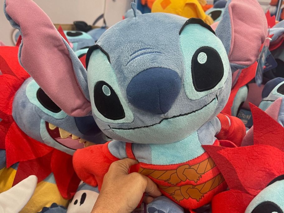 a womans hand holding a costumed stitch plush