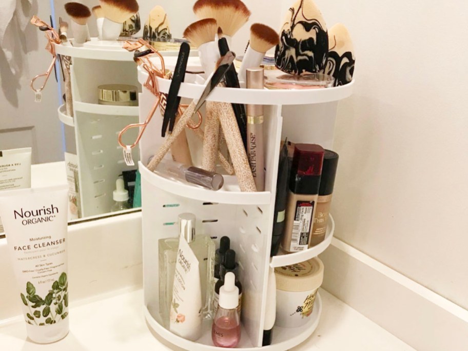 white rotating makeup organizer full of beauty products on bathroom counter