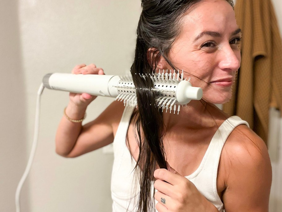 woman using white styler on hair 