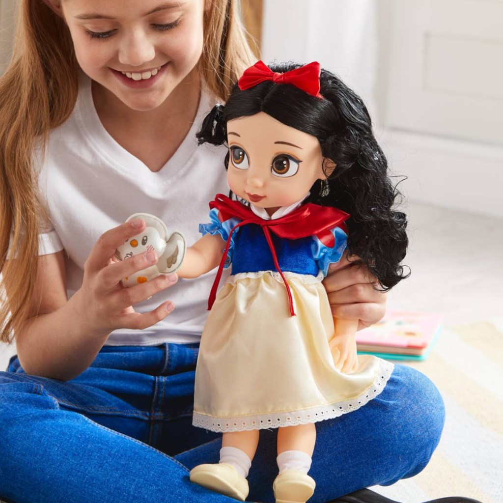 girl holding large snow white doll