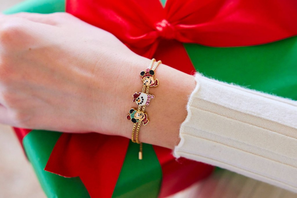 wrist wearing gold baublebar bracelet with mickey and minnie