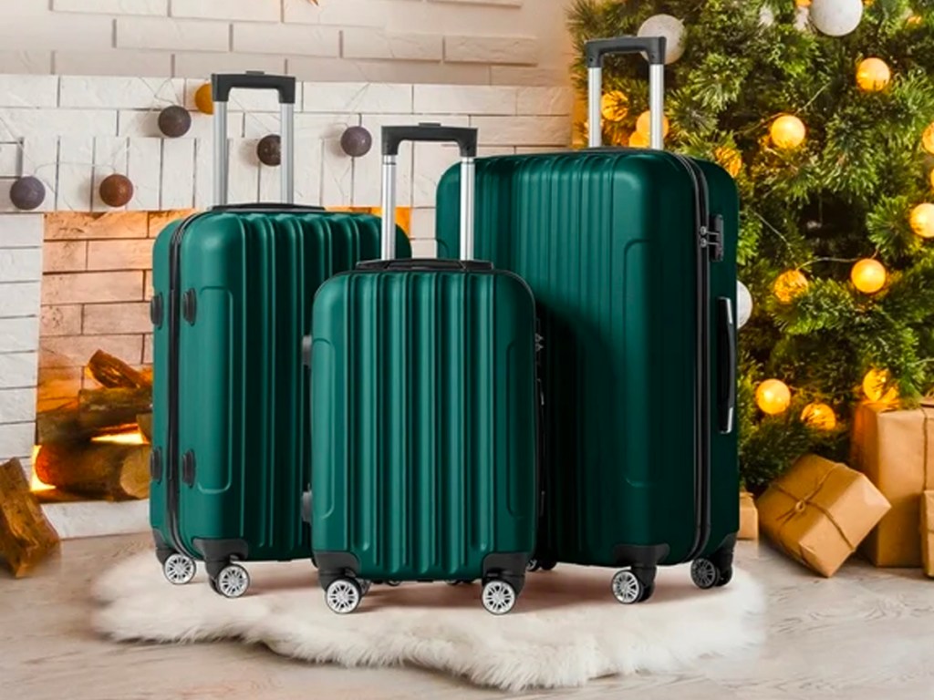 dark green 3 piece luggage spinner set next to christmas tree