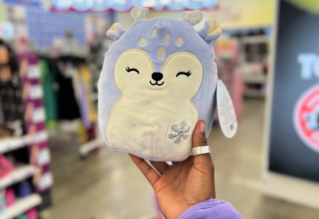 hand holding up a squishmallows fawn inside a five below store