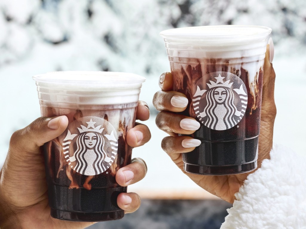 two hands holding Starbucks cold foam drinks outside