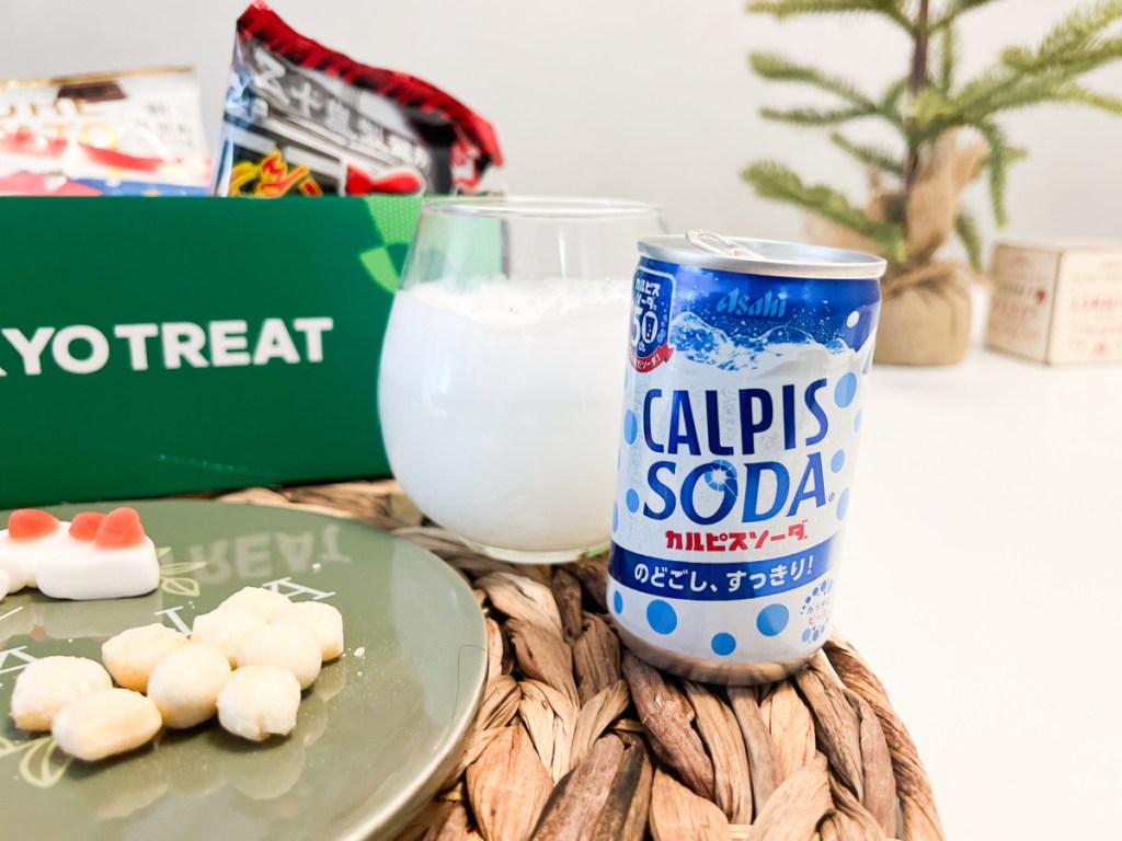 calpis japanese soda in glass next to can and treat box
