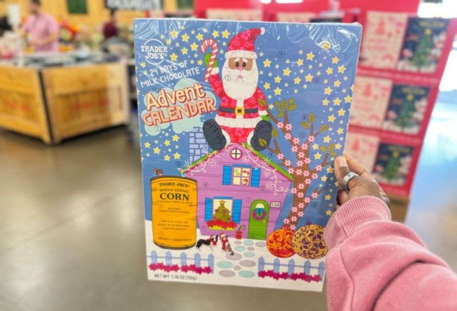 a womans hand holding a trader joes chocolate advent calendar in a store