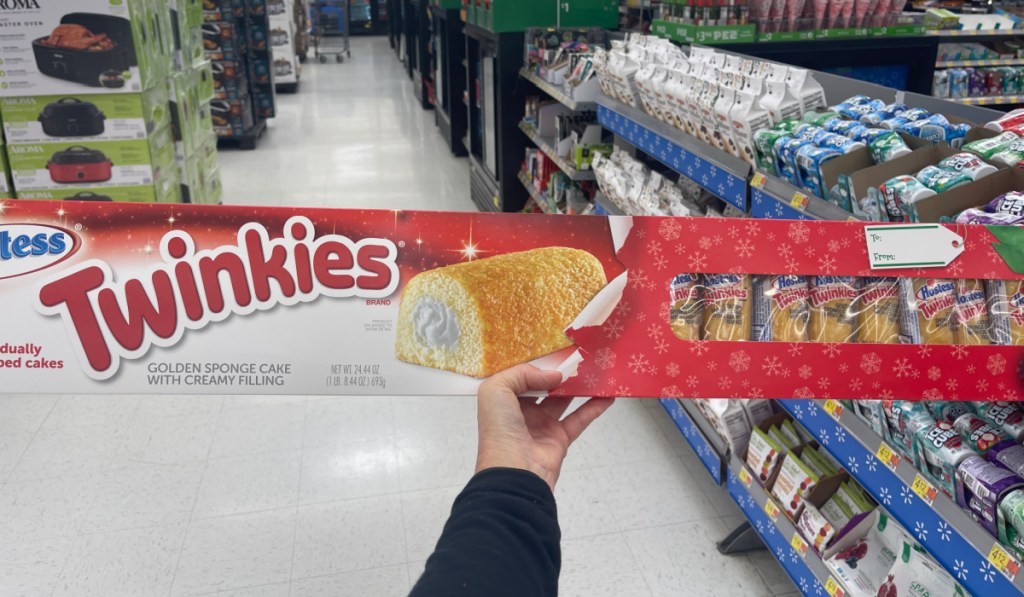 hand holding up a huge long box filled with hostess twinkies inside of walmart
