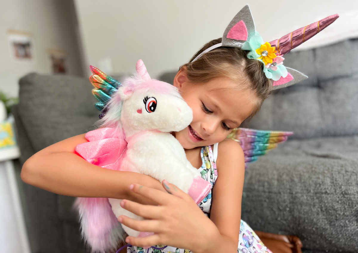 smiling young girl holding a plush unicorn