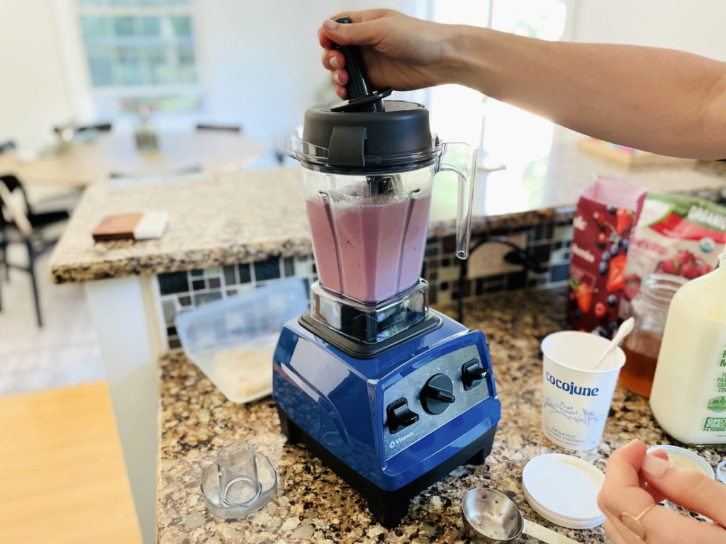 woman's arm holding a tamper in a vitamix explorian 2.0 blender