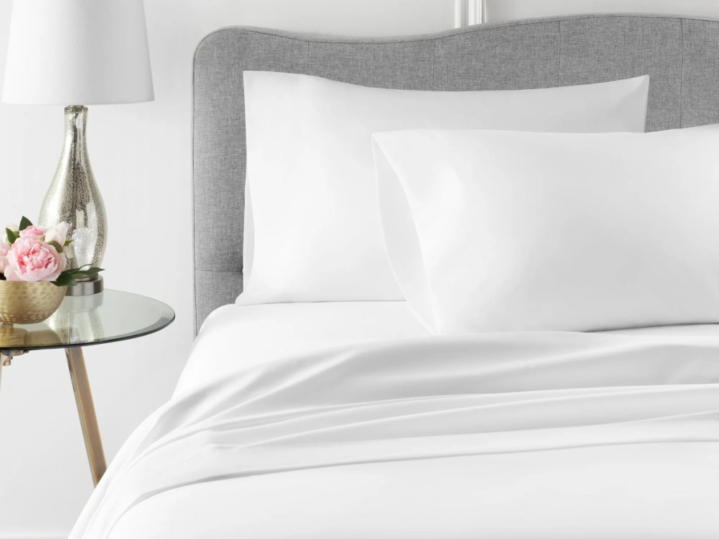 white sheets on bed with gray headboard