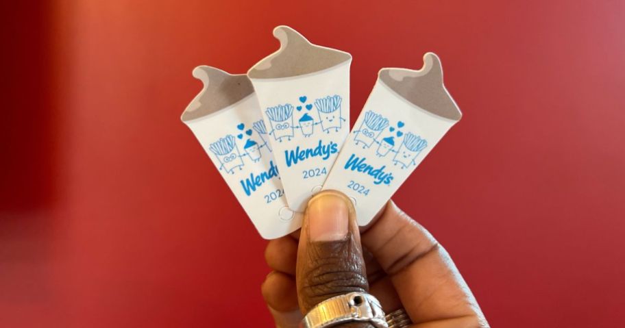a womans had displaying 3 fanned out wendys frosty key tags